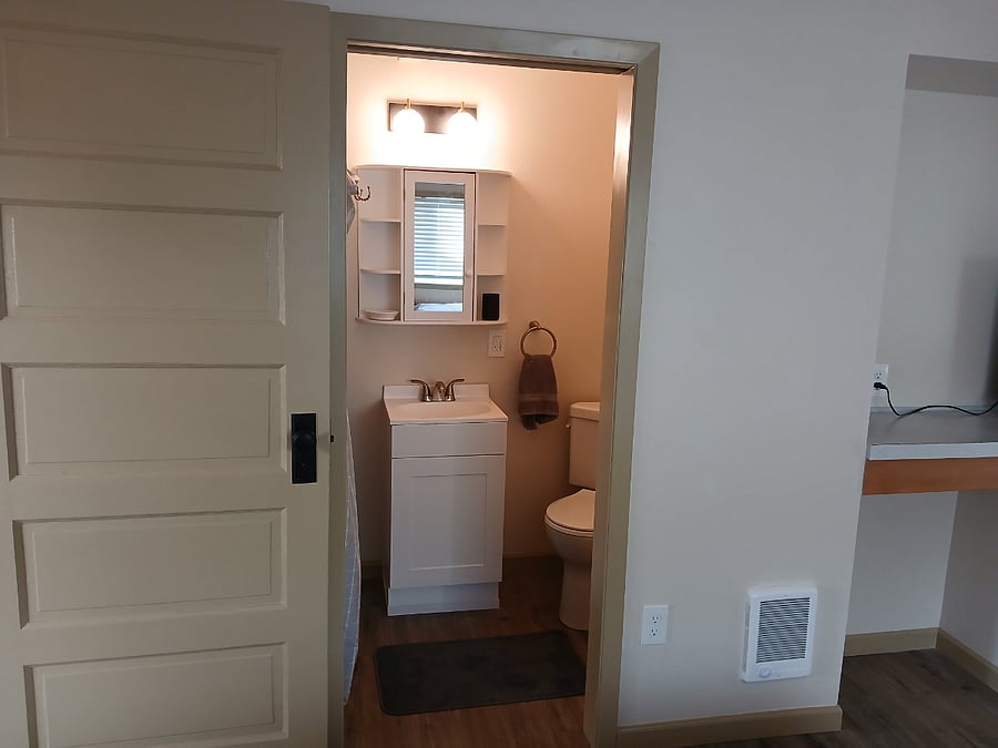 New bathroom with corner toilet and shower.