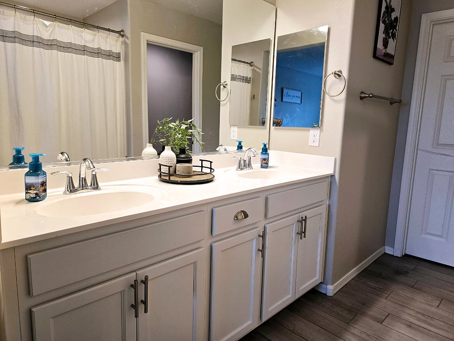 En suite bathroom with soaking tub, dual sinks, and separate toilet room.