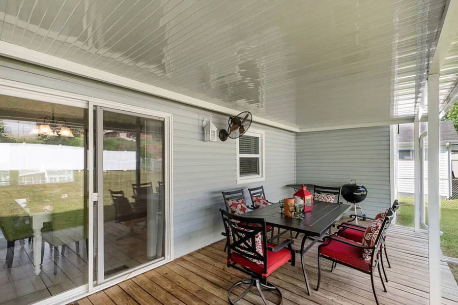 Covered back porch has a grill and dining area with seating for six