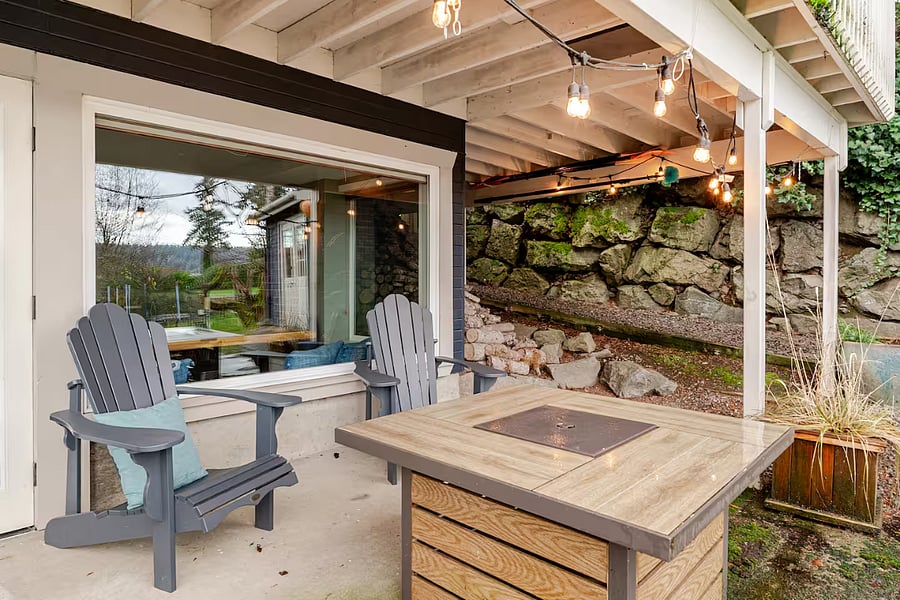 Covered patio outside the suite. Relax in the Adirondack chairs with warmth and ambiance of the fire table. The view looks out to the backyard and a wetland area, which is a bird watchers delight.
