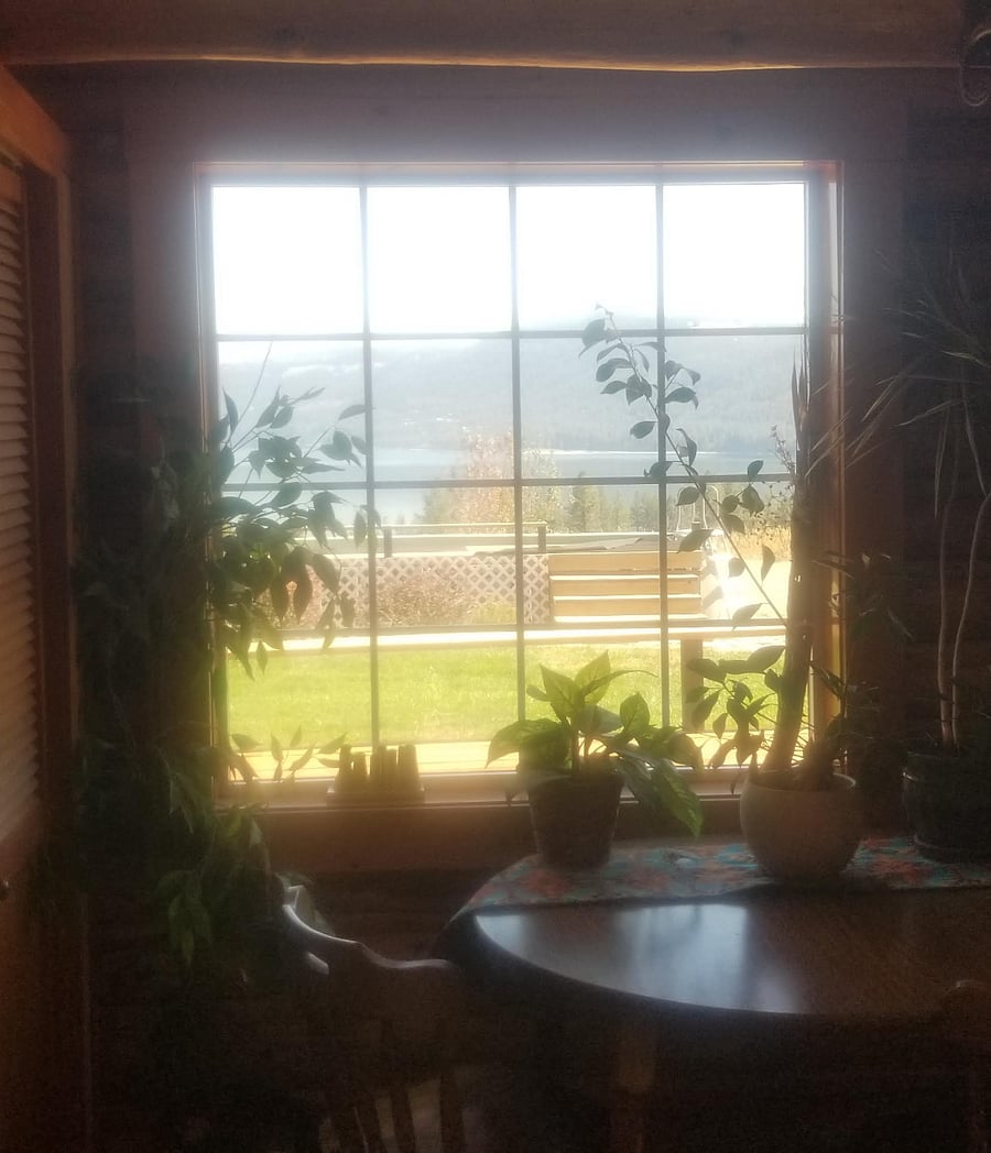 view from small table and chairs in entry room w/ wood stove, tile floors, small chest freezer and storage