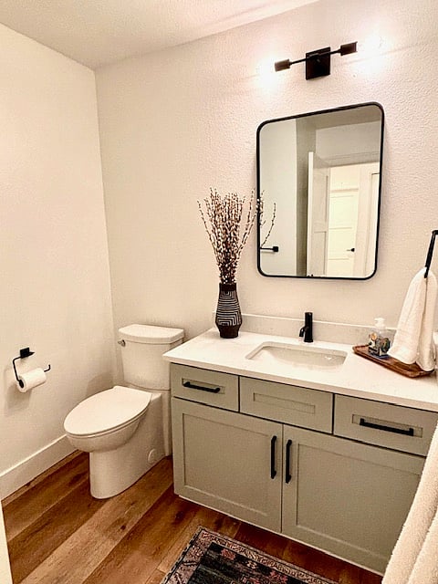 The contemporary flooring, with its smooth finish and subtle pattern, adds a touch of sophistication underfoot while tying the design together seamlessly. A pristine new toilet ensures both functionality and style, enhancing the space's polished look.