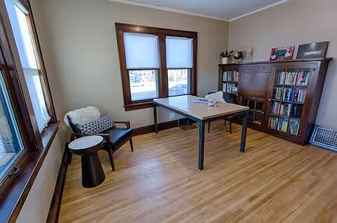 Our Library/Office is located just off the living room, immediately to your left as you enter the front door.  Help yourself to our book collection (no library card needed!) and ponder  the We Are All Criminal photo essays by local artist and social justice advocate Emily Baxter.