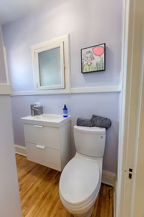 The upstairs 1/2 bath is accessible by the common hall that connects to all three bedrooms.  Mixed media Girl with pink balloon by local artist Katie Pratt. 