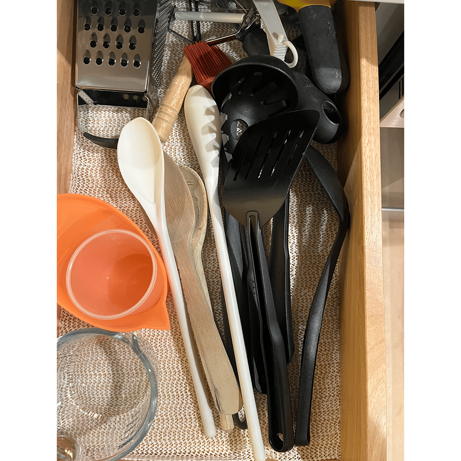 Assorted cook ware items, measuring cups, cheese grater, spoons and spatulas.