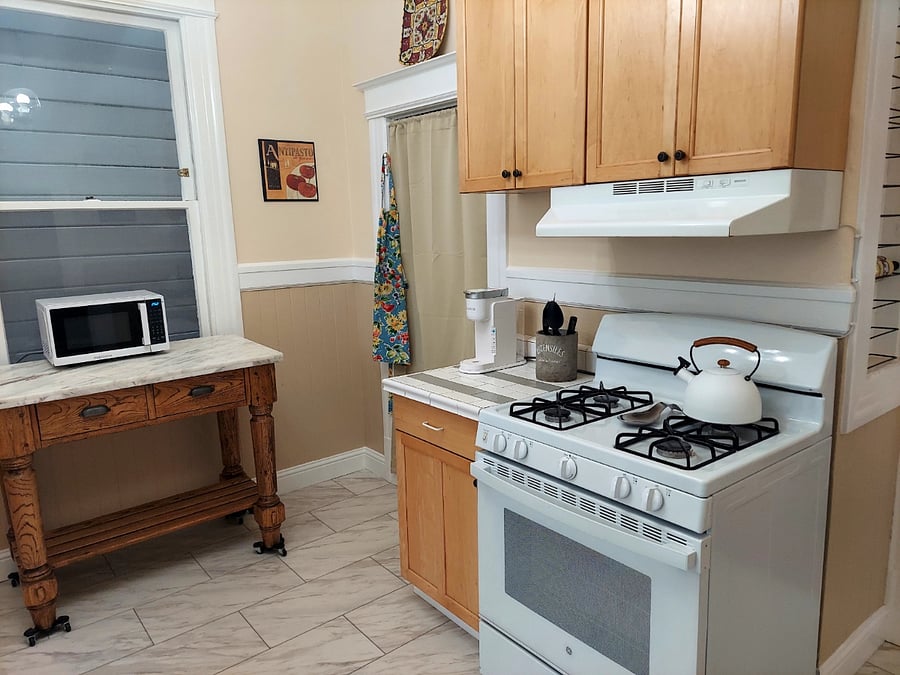 Kitchen with microwave, coffee maker, cooking supplies, cleaning supplies, etc.