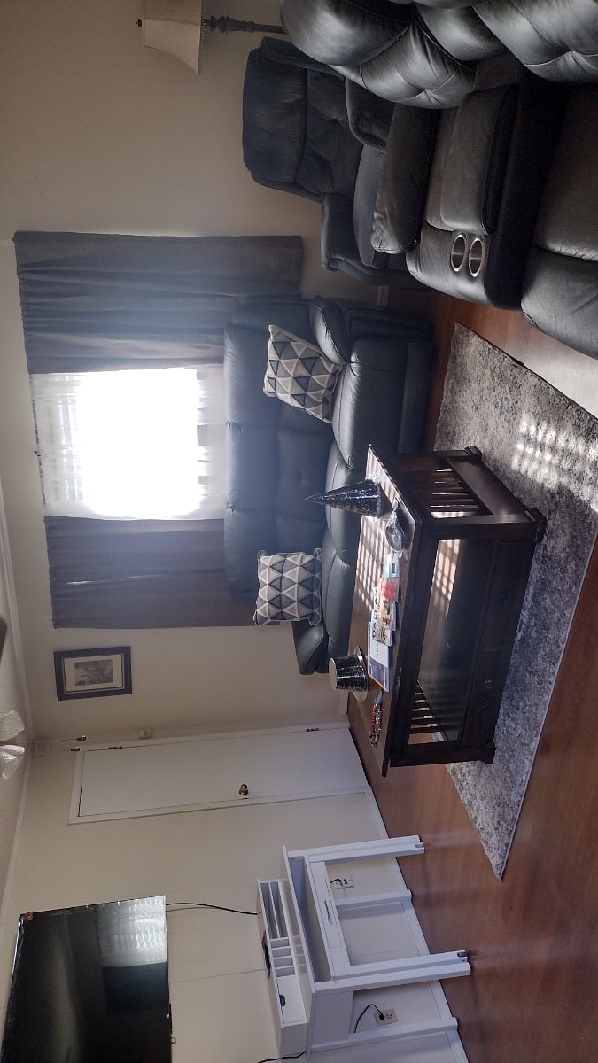 A large living room with a 65 inch screen to watch your favorite movies . Reclining couches,