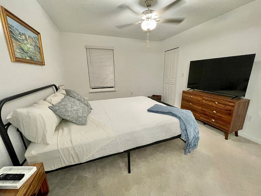 The main bedroom features a queen-size bed, a smart TV, a dresser, a walk-in closet, and an additional closet perfect for storage.