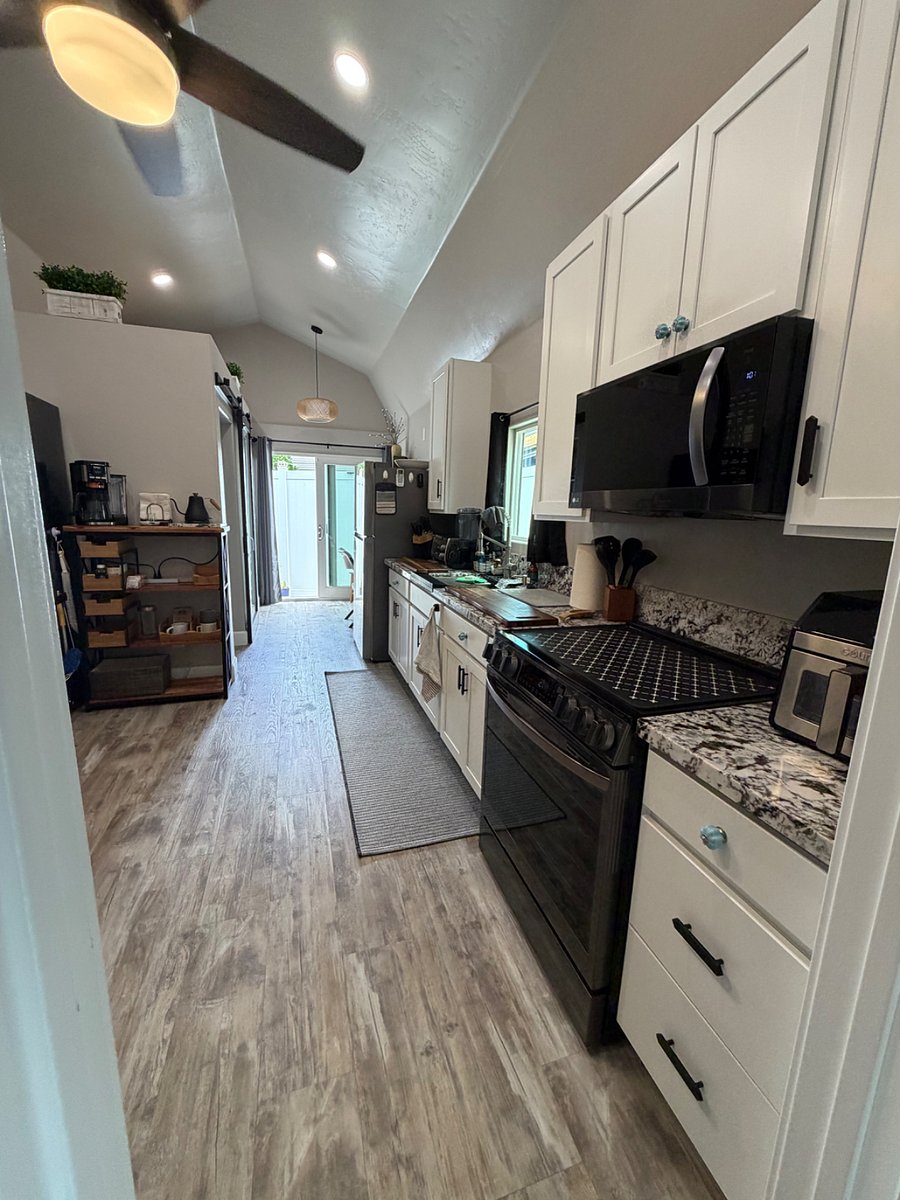 Kitchen with full size e-stove, full size microwave, and cabinets stocked with kitchen essentials. Includes coffee/tea station.