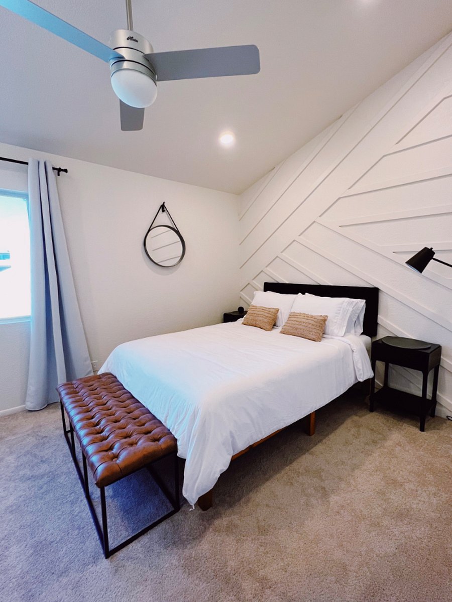 Second bedroom featuring vaulted ceilings, queen memory foam mattress, custom feature wall, desk, ceiling fan, desk and views of the pool.