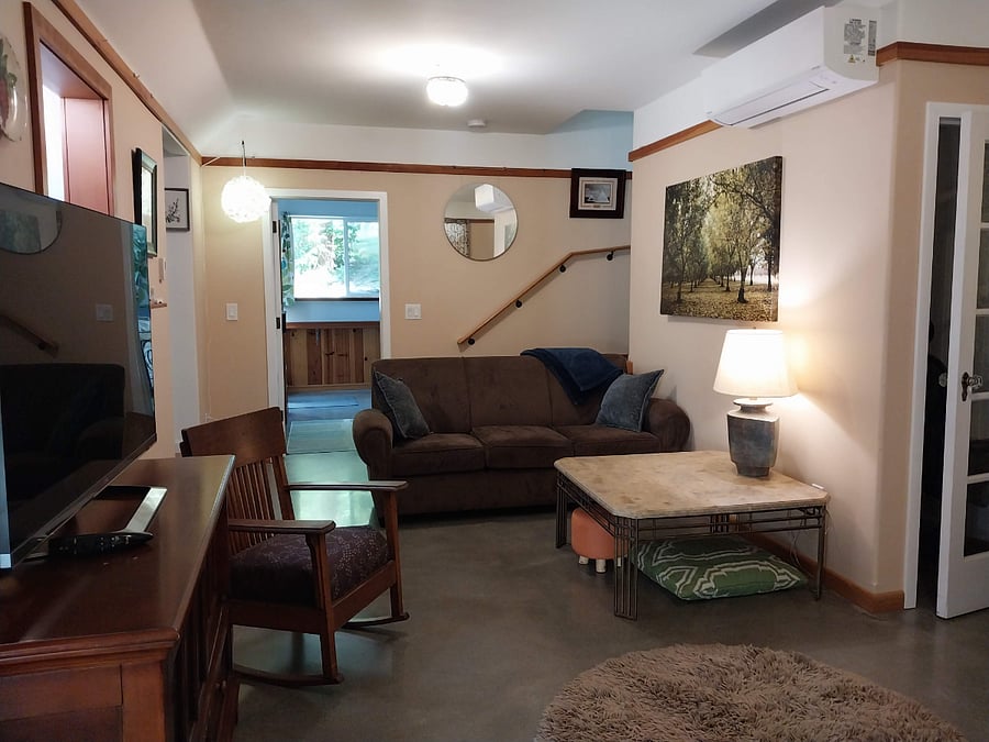 Living room with door to BR 2 and the way to the back patio. Stairs lead to deck and closed off bedroom upstairs.2026