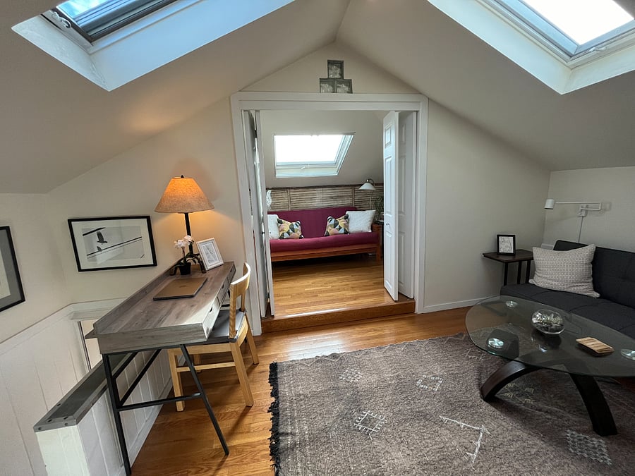 Livingroom area with workspace and couch; second bedroom with bifold doors for privacy