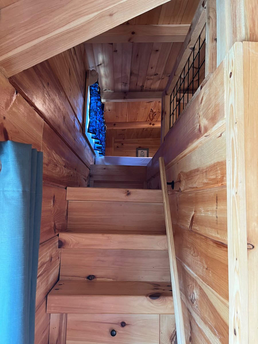Stairs with storage lead up to a loft with a second queen bed.
