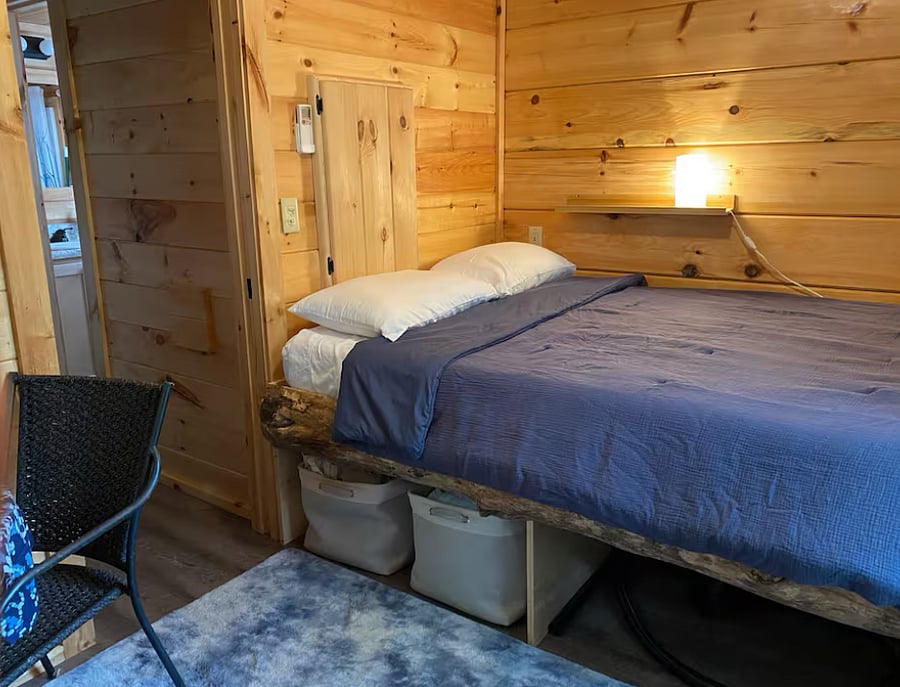 The main bedroom has a queen bed, small table, and bureau for clothing storage.