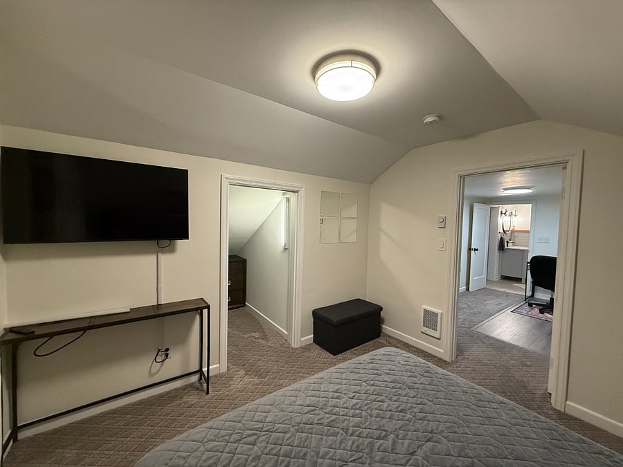 Bedroom with queen-size bed, wall-mounted smart TV, and walk-in closet