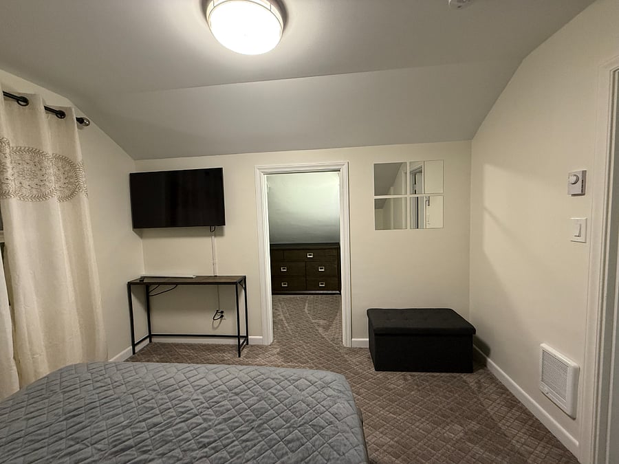 Bedroom with queen-size bed, wall-mounted smart TV, and walk-in closet