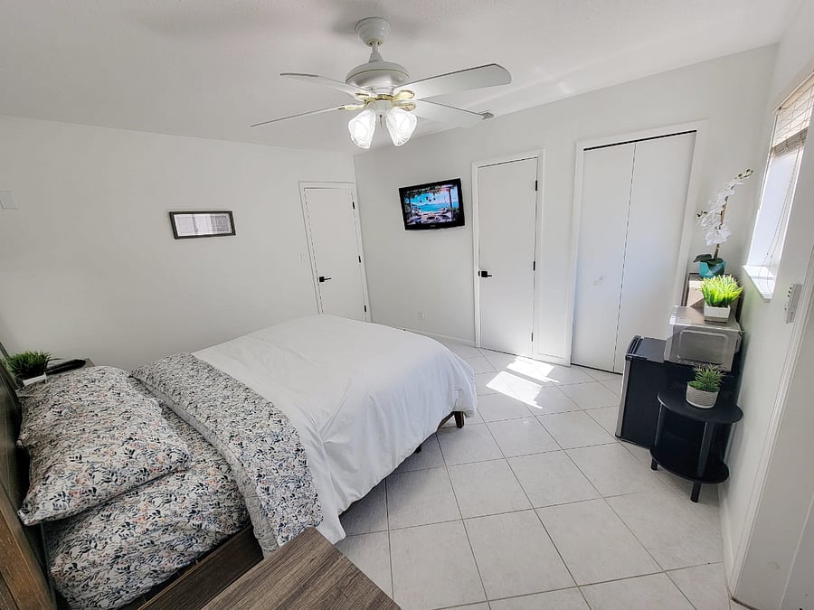 View of Tv, 2 closets, door to bathroom, chair, table, fridge, microwave. 