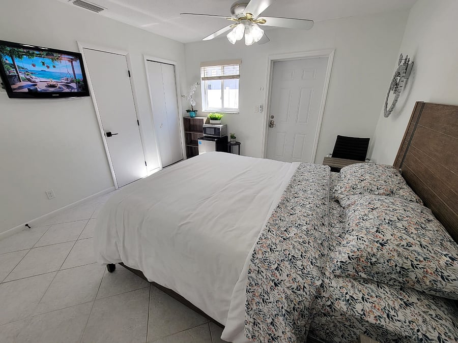View of Tv, 2 closets, outside entry/exit, chair, table, fridge, microwave. 