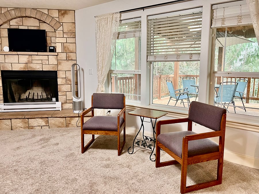 Primary bedroom includes a wood-burning fireplace that is serviced each autumn. Looks out over a private deck with forest view beyond.