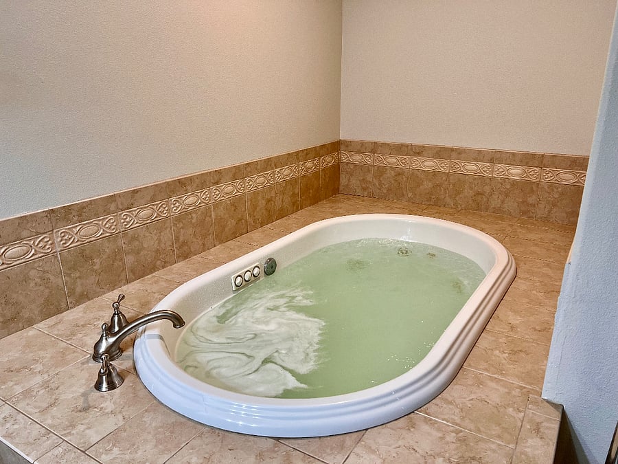 Large bathroom with double vanity, walk-in shower, separate toilet room, large soaking jacuzzi bath tub, and sauna. 