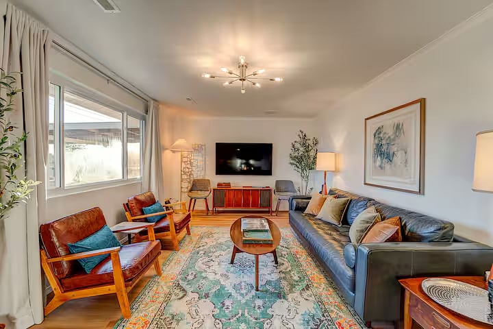 The large picture window allows an abundance of natural light. The lamps and ceiling fixture are on dimmers for guests to adjust. Multiple seating options can accommodate a larger group. Art lovers will notice the various pieces throughout the home.