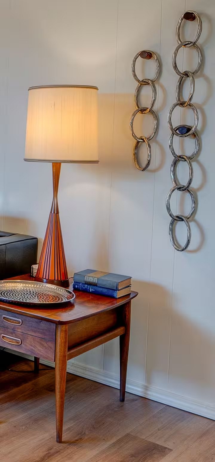 Authentic mid-century modern side table and lamp paired with sculptural wall art.