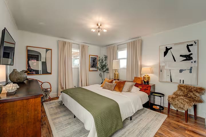 The primary bedroom is a retreat with vintage and modern style. The king mattress is chemical free & medium-firm, with organic bedding, and an authentic vintage Henredon designed headboard. Multiple lamps and the ceiling fixture are on dimmers.