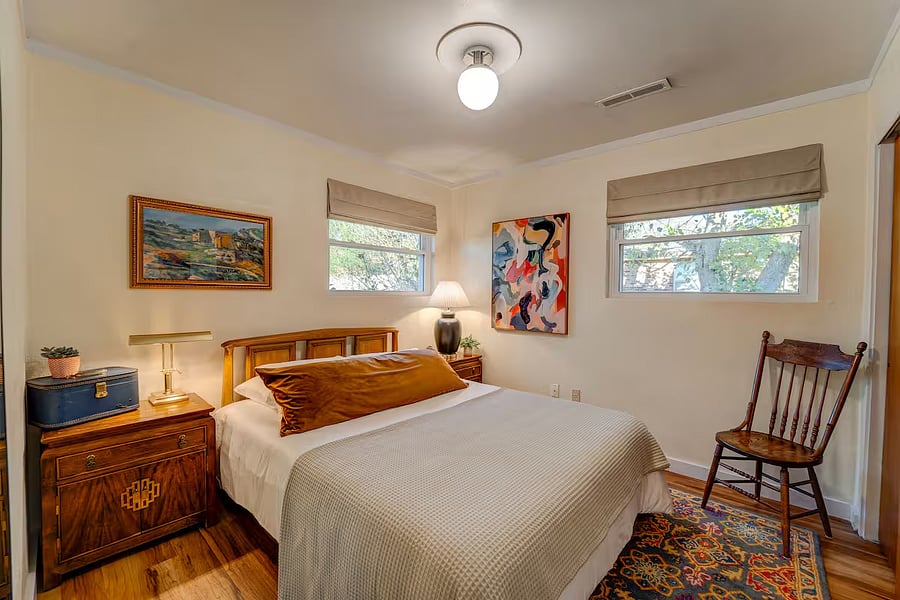 Relaxing guest bedroom with authentic mid-century headboard, chemical free, medium-firm queen mattress, organic bedding, vintage furniture, soft lighting, and closet.