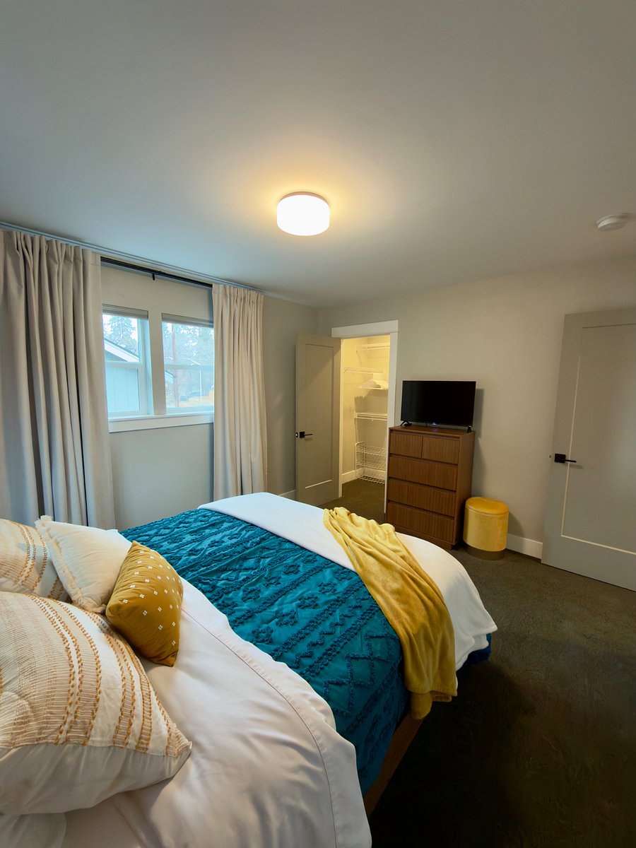 Tenant Bedroom with a queen size bed, two nightstands, dresser, smart TV, storage stool and blackout curtains.