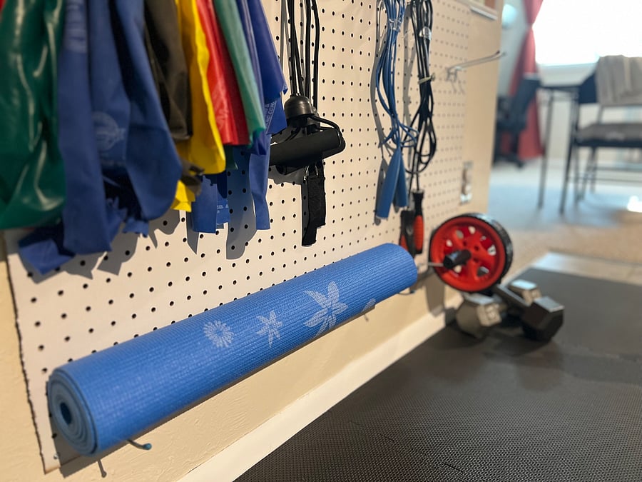 Small exercise nook with resistance bands, yoga mat & dumbbells for light workouts.