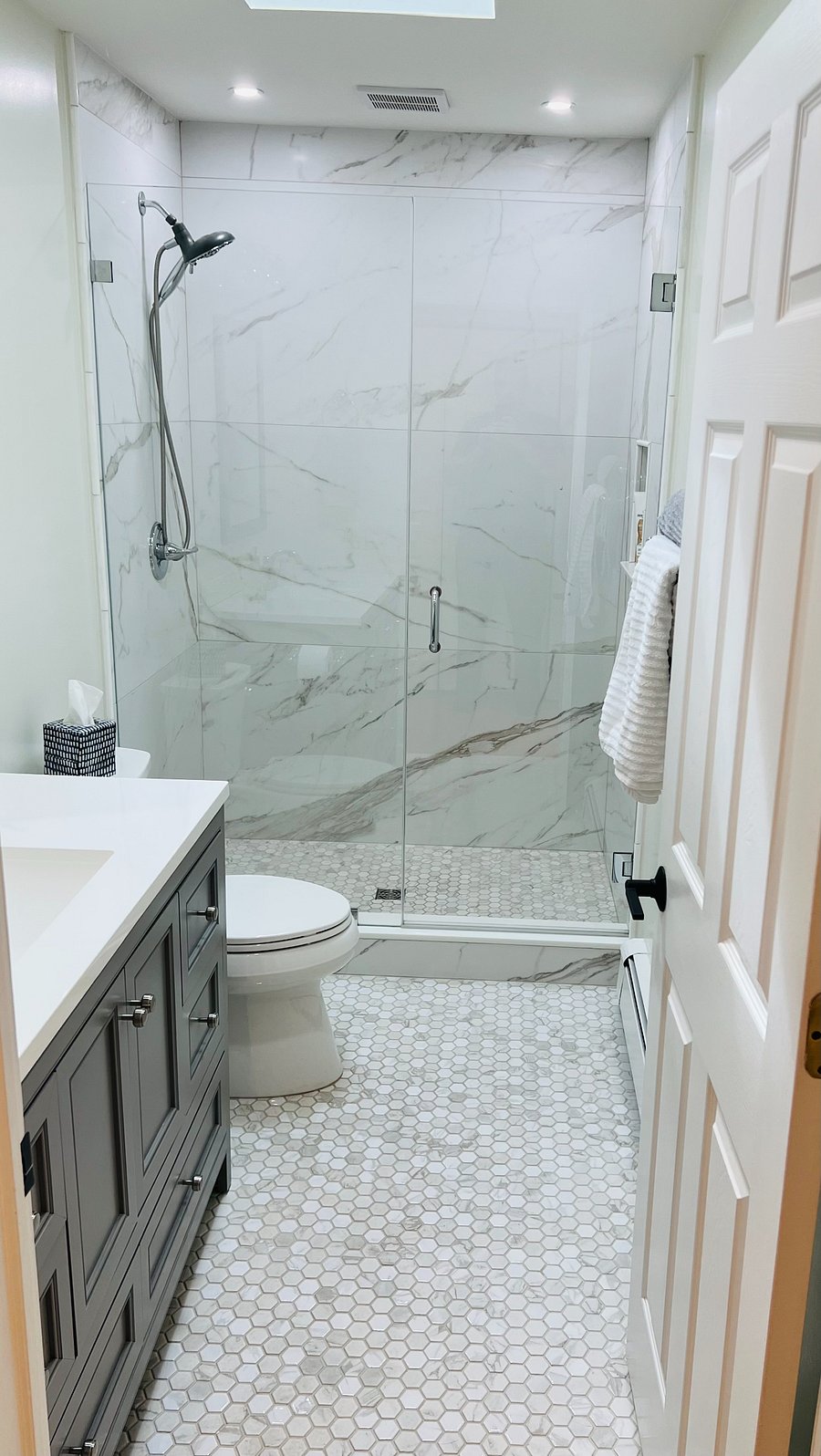 Newly remodeled bathroom with large walk-in marble shower, vanity and skylight