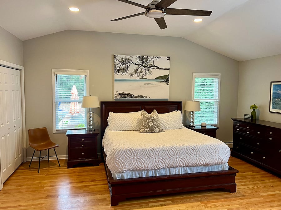 Large (20'x20') master bedroom with vaulted ceilings, 3 windows, king sleigh bed, 2 matching nightstands, dresser, and chest, bookshelf, TV armoire, wall-mounted Smart TV, 2 large double door closets
