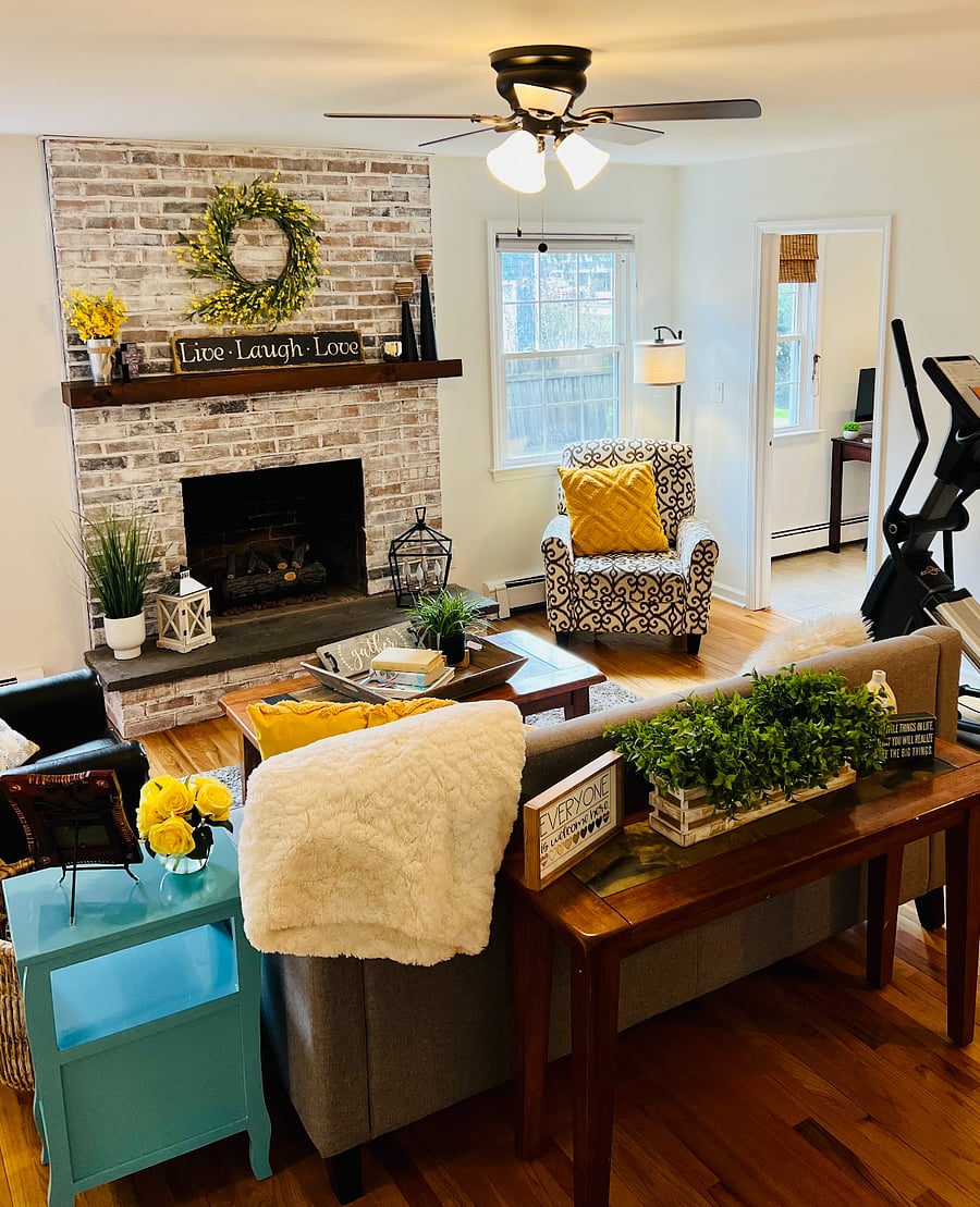 Large living room with working fireplace, 2 arm chairs, sofa, desk/chair, sofa, coffee table, wall-mounted Smart TV, elliptical machine