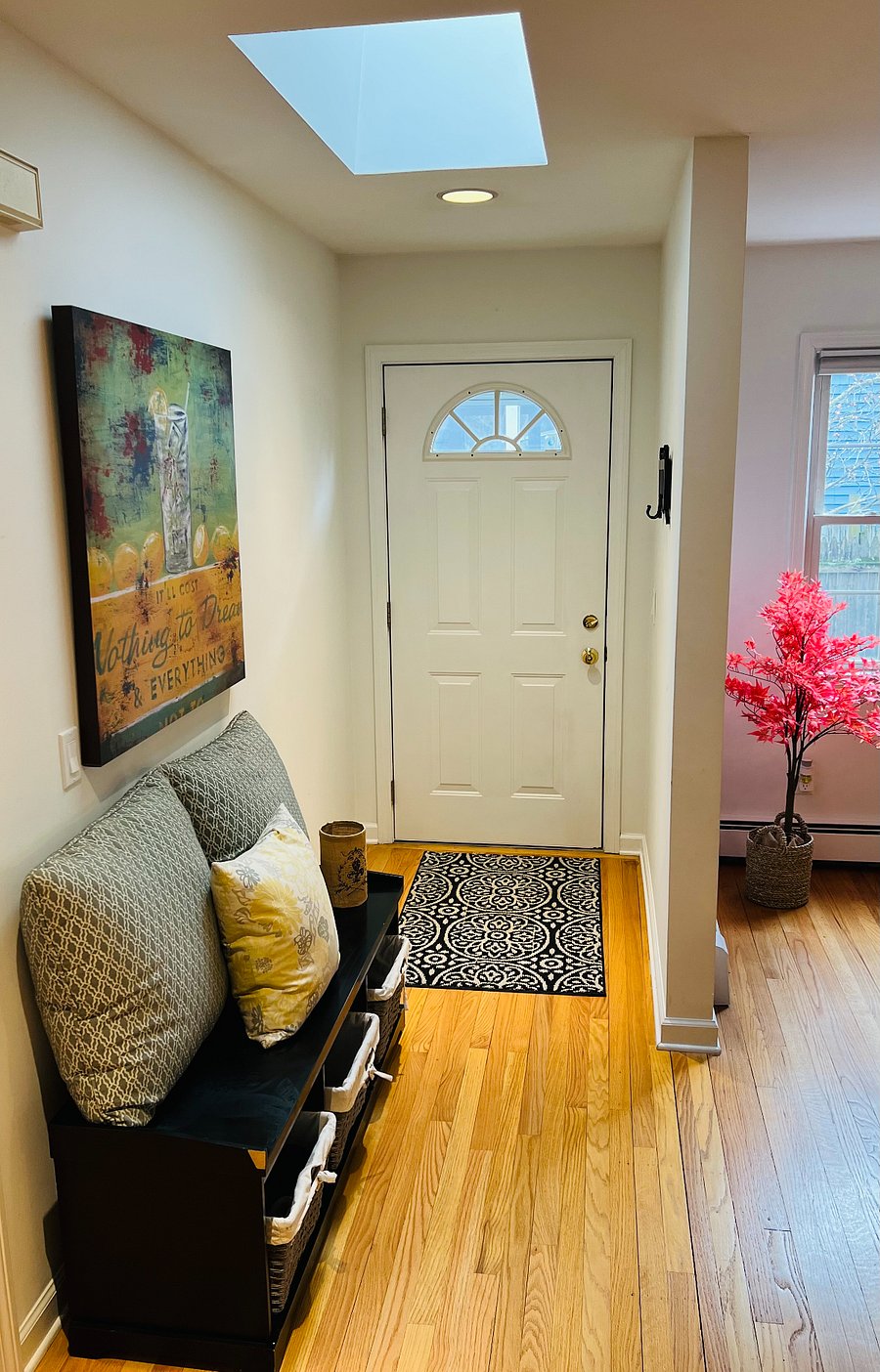 Foyer with bench, storage, skylight, and wall-mounted coat rack