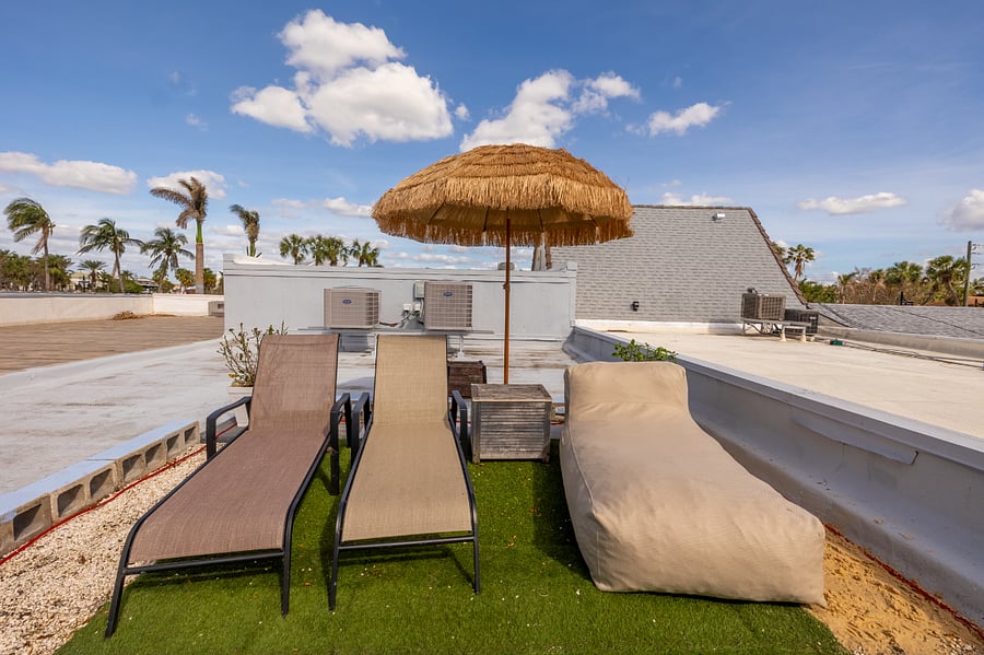 2 lounge chairs, a daybed and palapa style umbrella