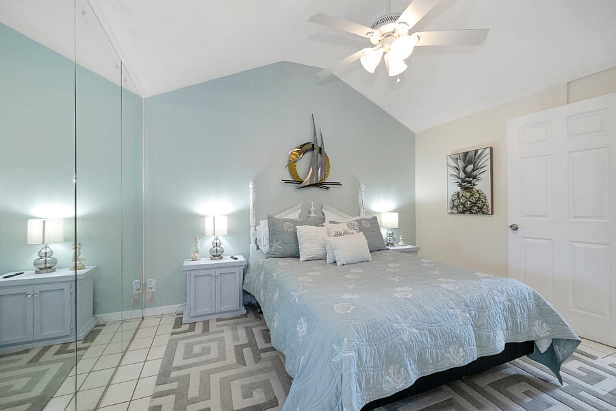 2nd bedroom with mirrored wall, side tables, charging pads, lamps with usb ports, smart tv, clothing rack and small dresser