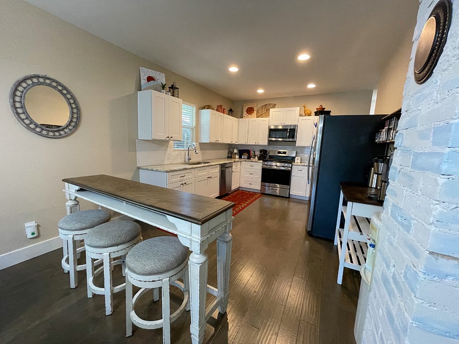Kitchen with bar seating displaying the stainless steel appliances and farmhouse sink.