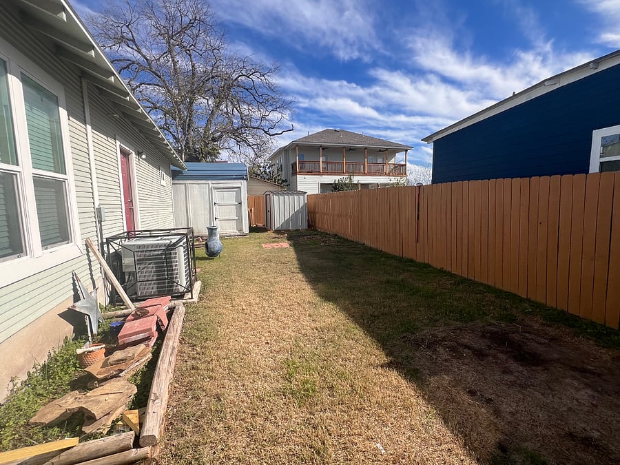 Back yard featuring two flower beds and two storage sheds.