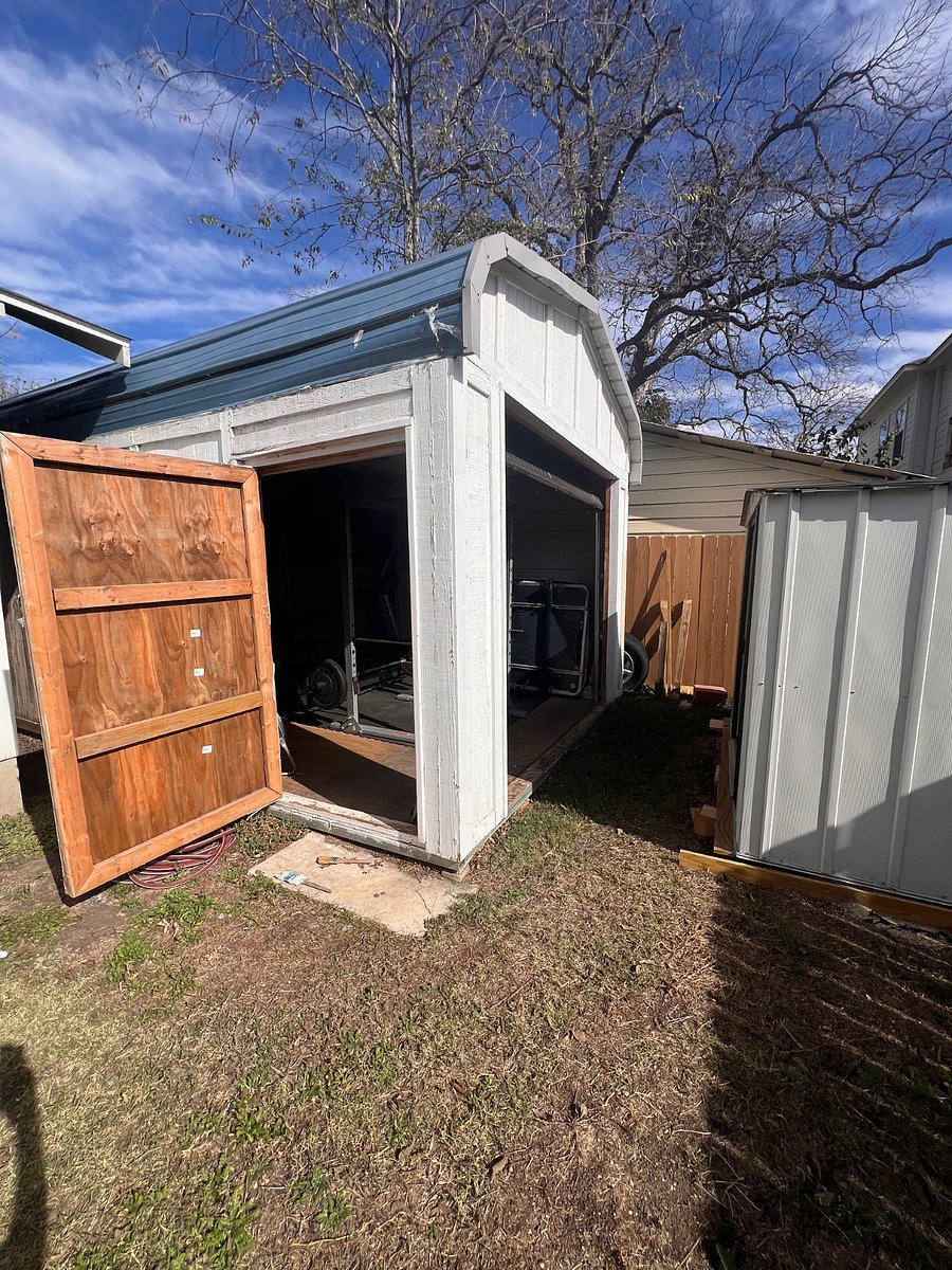 Large storage shed with garage door and entrance door open.