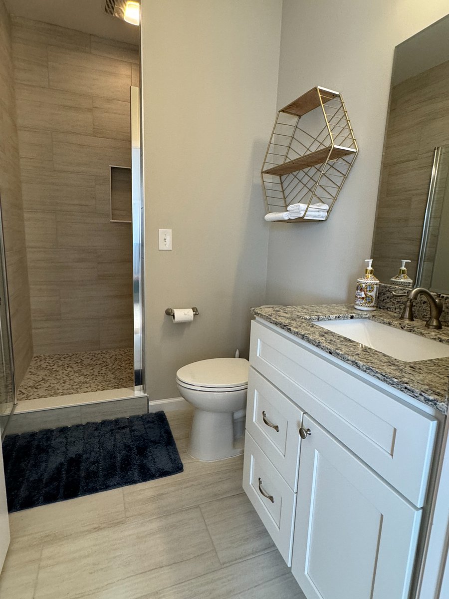 Bathroom with large tiled shower and vanity with granite counter top