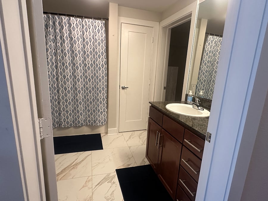 Oversize tub with shower, walk in closet with chest of drawers and a linen closet.