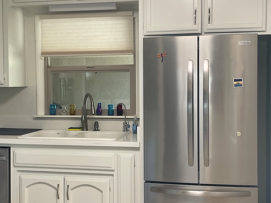 Double filtered water dispenser to the right of sink facet and refrigerator.