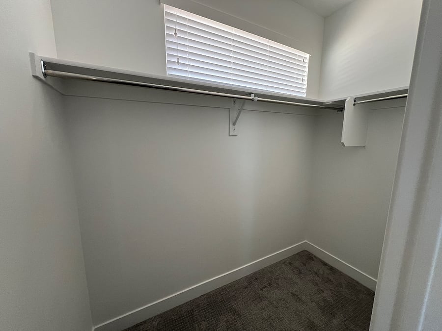 Walk in closet with hangers and laundry basket. 
