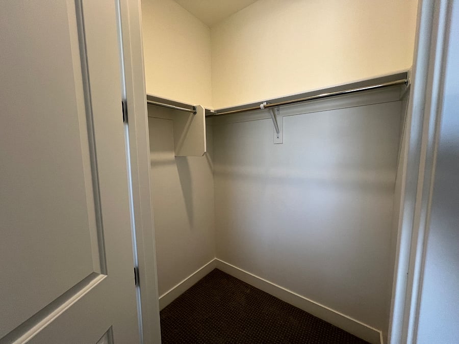Walk in closet with hangers and hamper