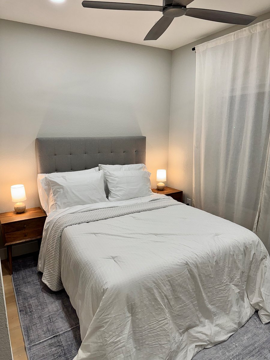 Queen sized bed in primary bedroom with black out shades