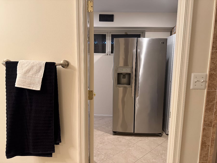 Full size refrigerator just outside of bathroom door