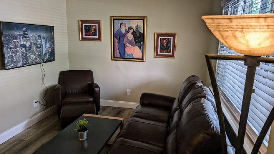 Living room with couch, chair. coffee table, Smart TV and window looking onto the porch.