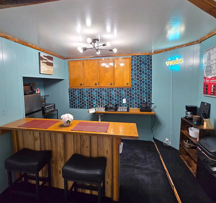 Kitchnette with covection over, cook top, plates, silverware, sink and coffee maker
