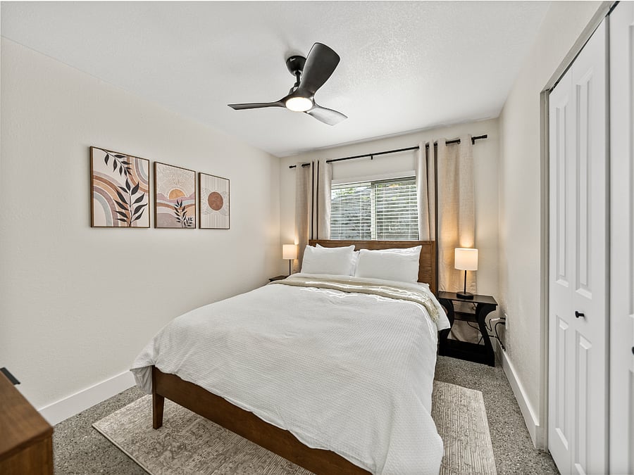 Cozy and modern bedroom featuring a queen bed, terrazzo floors, blackout curtains, and a mounted TV for your entertainment. Clean lines and warm tones make this space the perfect place to relax and unwind.