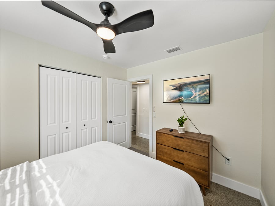 Cozy and modern bedroom featuring a queen bed, terrazzo floors, blackout curtains, and a mounted TV for your entertainment. Clean lines and warm tones make this space the perfect place to relax and unwind.